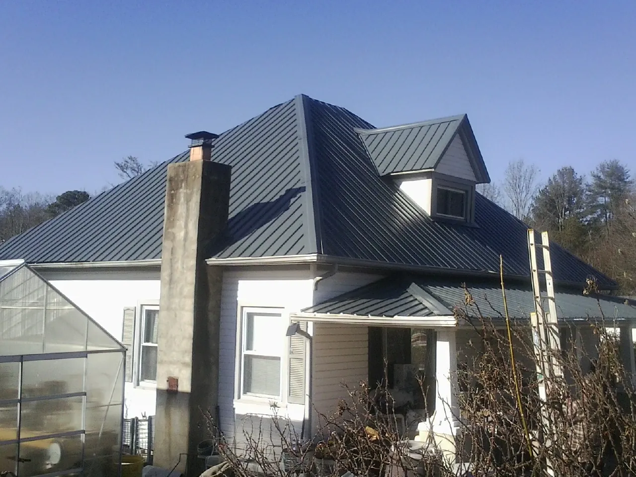 Dark blue standing seam metal roof on a white farmhouse with dormer — Slate & Tile Roof Repair by Roofing Brothers in Trevorton