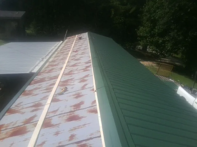 Old rusted panels beside newly installed green metal roofing — Wind Damage Roof Repair by Roofing Brothers in Trevorton