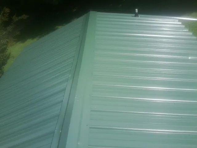 New green metal panels meeting at the ridge of a roof — Flat Roof Repair work by our crew in Trevorton