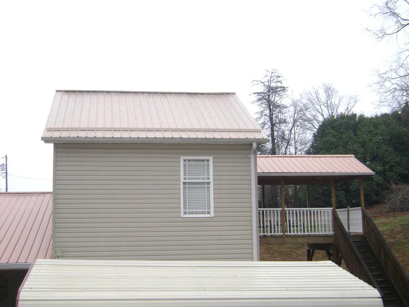 Tan metal roofs on a two story addition and attached porch, from a Roof Replacement job in Trevorton